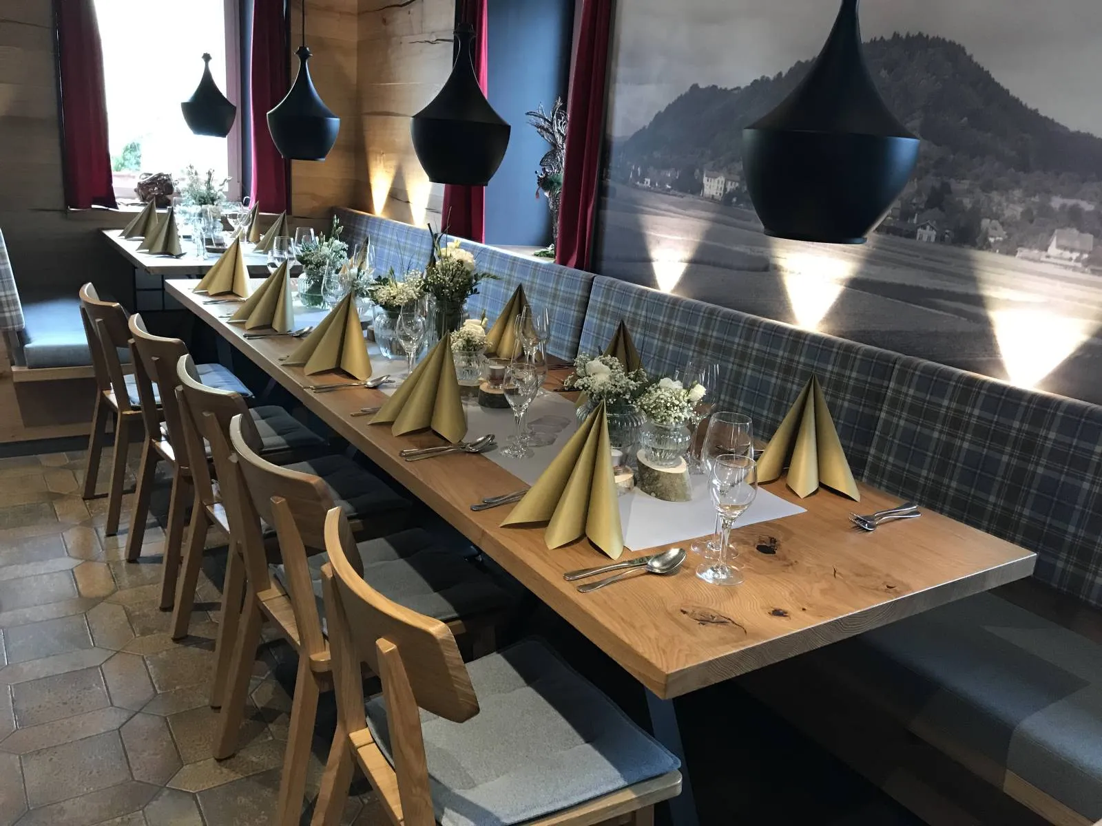 Tafel mit grauen Polsterbänken und goldenen Servietten
