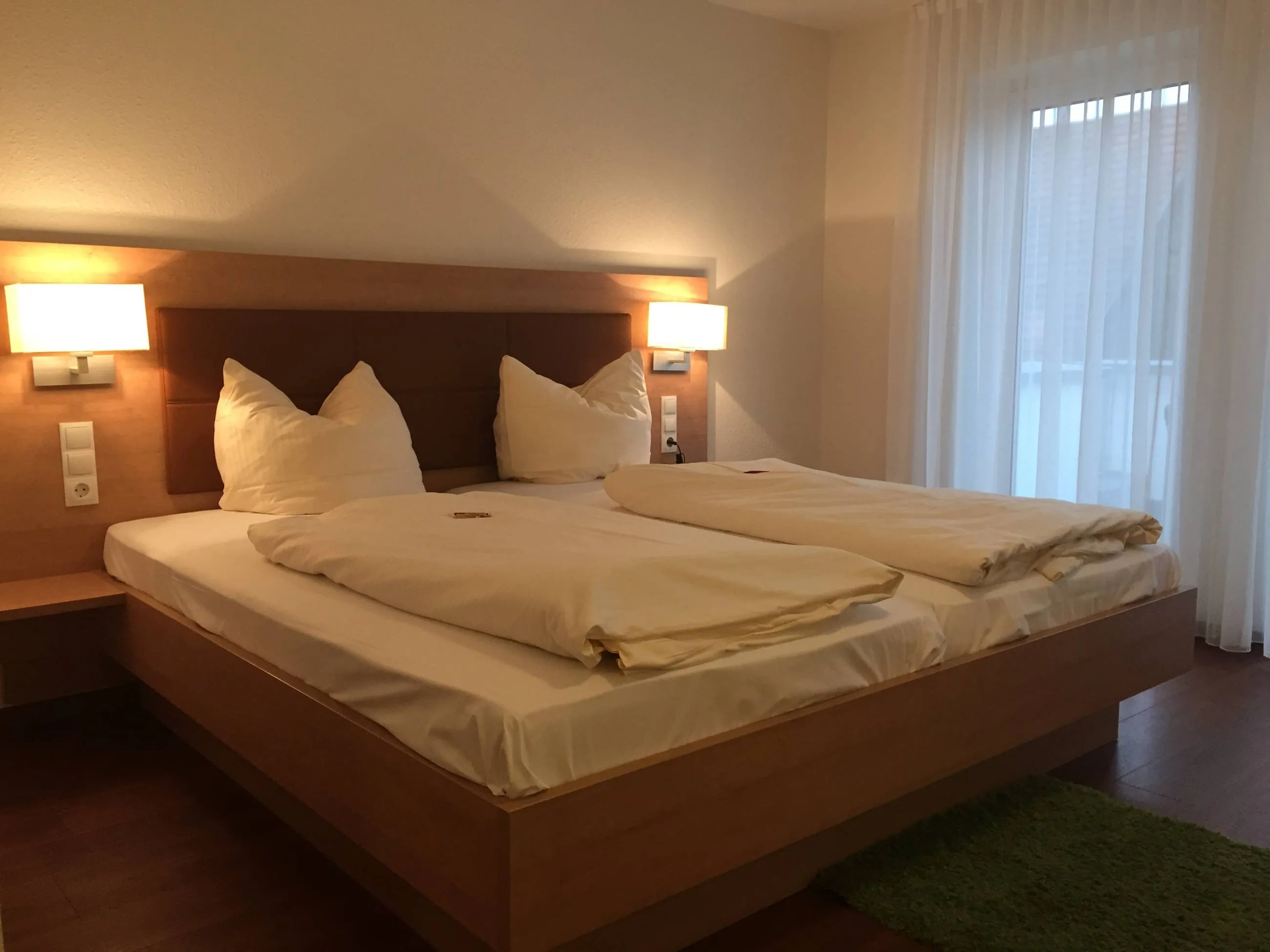 Helles Doppelzimmer mit Holzkopfteil und Leselampen